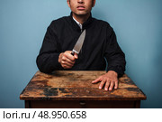 Dangerous man at table with a knife. Стоковое фото, агентство Ingram Publishing / Фотобанк Лори