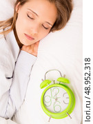 Beautiful woman sleeping with alarmclock on the bed . Стоковое фото, агентство Ingram Publishing / Фотобанк Лори