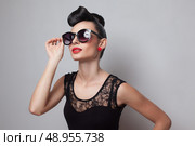 Young fashionable woman in round sunglasses posing in guipure dress. Red lips. Updo, twisted high bun. top knot. Стоковое фото, агентство Ingram Publishing / Фотобанк Лори