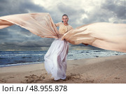 Fashionable model posing in extremely long dress on the seashore. Стоковое фото, агентство Ingram Publishing / Фотобанк Лори