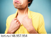 Man with a sad look on his face is pulling at his shirt collar. Стоковое фото, агентство Ingram Publishing / Фотобанк Лори