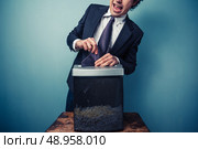 Clumsy businessman with his tie stuck in a paper shredder. Стоковое фото, агентство Ingram Publishing / Фотобанк Лори