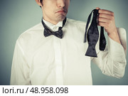 Young man is sad he couldn’t tie his own bow tie. Стоковое фото, агентство Ingram Publishing / Фотобанк Лори