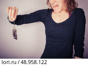 A squeamish and disgusted woman is holding a dead mouse by it’s tail. Стоковое фото, агентство Ingram Publishing / Фотобанк Лори