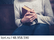 Nervous young man sitting on a sofa is clutching a book. Стоковое фото, агентство Ingram Publishing / Фотобанк Лори