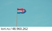 Croatian national flag waving proudly on a pole against a bright clear blue sky. Стоковое видео, видеограф Igor Tichonow / Фотобанк Лори