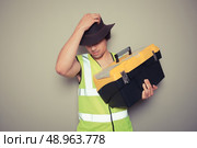 A cowboy builder with a big tool box is pulling silly faces and gesturing. Стоковое фото, агентство Ingram Publishing / Фотобанк Лори