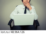 Young businessman is sitting in an office chair and is startled by his laptop. Стоковое фото, агентство Ingram Publishing / Фотобанк Лори