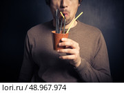 A silly young man is drinking from a leather cup with a bunch of colorful straws. Стоковое фото, агентство Ingram Publishing / Фотобанк Лори