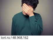 Young man is hiding his face in the palms of his hands. Стоковое фото, агентство Ingram Publishing / Фотобанк Лори