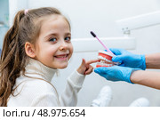 Portrait of a girl has fun and puts her finger into a model of jaws while sitting in a dental office. Children's dentistry. Children's teeth care. Стоковое фото, фотограф Ирина Михайличенко / Фотобанк Лори