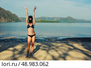 A strange young woman is posing on a tropical beach in a bikini and a balaclava. Стоковое фото, агентство Ingram Publishing / Фотобанк Лори