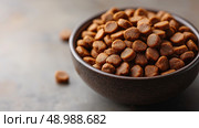 Dry pet food in a bowl showcasing a close-up view of kibble. Сухой корм для домашних животных в миске, крупным планом показаны кусочки. Стоковое AI-изображение, AI-художник Katsiaryna Repich / Фотобанк Лори