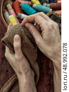 women's hands in the process stepania holey socks on the background of sewing thread. Стоковое фото, агентство Ingram Publishing / Фотобанк Лори
