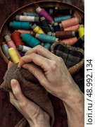 hands in the process stepania holey socks on the background of sewing thread. Стоковое фото, агентство Ingram Publishing / Фотобанк Лори