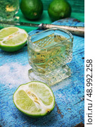 glass alcoholic drink and lime fruits on wooden texture.Selective focus. alcoholic cocktail with additions of lime. Стоковое фото, агентство Ingram Publishing / Фотобанк Лори