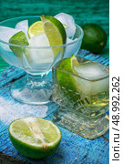 glass alcoholic drink and lime fruits on wooden texture.Selective focus. alcoholic cocktail with additions of lime. Стоковое фото, агентство Ingram Publishing / Фотобанк Лори
