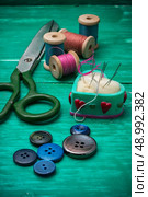 scattering of buttons,thread and needle on turquoise background.Selective focus. Стоковое фото, агентство Ingram Publishing / Фотобанк Лори