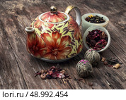 teapot and scattered tea leaves on vintage wooden background. brewed leaf tea in glass jar. Стоковое фото, агентство Ingram Publishing / Фотобанк Лори