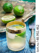one glass alcoholic drink and lime fruits on wooden texture.Selective focus. alcoholic cocktail with additions of lime. Стоковое фото, агентство Ingram Publishing / Фотобанк Лори