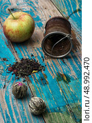 tea leaves and red apple on wooden background.The image is tinted in vintage style. tea leaves and red apple on wooden background. Стоковое фото, агентство Ingram Publishing / Фотобанк Лори