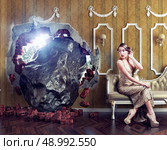 Meteorite enters the room, scaring the woman on the sofa. Photo combination creative concept. Стоковое фото, агентство Ingram Publishing / Фотобанк Лори