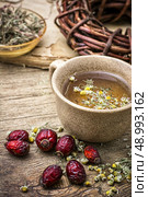 ceramic cup brewed with rose hips and chamomile in vintage rustic style. healing broth. Стоковое фото, агентство Ingram Publishing / Фотобанк Лори
