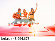 young group having fun on the beach playing guitar and dancing in a convertible car. Стоковое фото, агентство Ingram Publishing / Фотобанк Лори