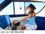 Kid girl pretending be a captain sailor cap in boat indoor holding wheel. Стоковое фото, агентство Ingram Publishing / Фотобанк Лори