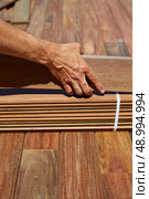 Ipe decking installation with carpenter hands holding tropical wood slats. Стоковое фото, агентство Ingram Publishing / Фотобанк Лори