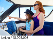 Kid girl pretending be a captain sailor cap with her mother in boat indoor. Стоковое фото, агентство Ingram Publishing / Фотобанк Лори