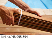 Ipe decking installation with carpenter hands holding tropical wood slats. Стоковое фото, агентство Ingram Publishing / Фотобанк Лори