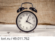 Classic black and white alarm clock on a wooden table. Стоковое фото, агентство Ingram Publishing / Фотобанк Лори