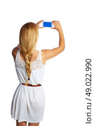 Blond tourist girl taking photos with smartphone on white background and braid. Стоковое фото, агентство Ingram Publishing / Фотобанк Лори