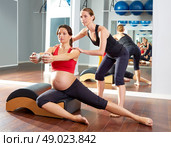 pregnant woman pilates side stretchs exercise workout at gym with personal trainer. Стоковое фото, агентство Ingram Publishing / Фотобанк Лори