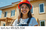 Female construction worker near house under construction. Young woman in orange protective helmet and overalls smiles against background of new building. Portrait of charming worker. Стоковое AI-видео, аниматор Ирина / Фотобанк Лори