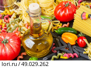 Olive oil with pasta. Jug of Olive oil with raw pasta and tomatoes . Стоковое фото, агентство Ingram Publishing / Фотобанк Лори
