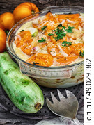 gratin of zucchini and yellow tomatoes . gratin of zucchini and yellow tomatoes on wooden background in glass bowl. Стоковое фото, агентство Ingram Publishing / Фотобанк Лори