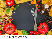 Pasta with ingridients with steel fork and knife,  copy space on black board. Стоковое фото, агентство Ingram Publishing / Фотобанк Лори