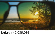 On a summer day, a man put on sunglasses to protect his eyes from the sun and admired the rising sun over the hills and fields. Close up. Стоковое видео, видеограф Strunov David / Фотобанк Лори