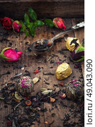 by spilling tea spoons. varieties of dry tea infuser scattered on wooden table. Стоковое фото, агентство Ingram Publishing / Фотобанк Лори