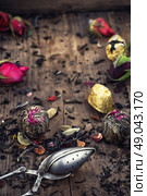 by spilling tea spoons. varieties of dry tea infuser scattered on wooden table. Стоковое фото, агентство Ingram Publishing / Фотобанк Лори