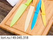 set of colorful ceramic knives on wooden cutting board. Стоковое фото, агентство Ingram Publishing / Фотобанк Лори