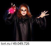 Young witch with red potion isolated on black. Стоковое фото, агентство Ingram Publishing / Фотобанк Лори