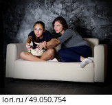 Two girls looks TV in dark room. Стоковое фото, агентство Ingram Publishing / Фотобанк Лори