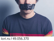 A young man has a big piece of black industrial tape covering his mouth. Стоковое фото, агентство Ingram Publishing / Фотобанк Лори