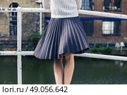 A young woman wearing a skirt is standing on a bridge by a canal and is relaxing whilst looking at an old building. Стоковое фото, агентство Ingram Publishing / Фотобанк Лори