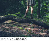 A young woman is standing on a log in a clearing in the forest. Стоковое фото, агентство Ingram Publishing / Фотобанк Лори