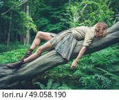A young woman is lying on a fallen tree in the forest surrounded by ferns. Стоковое фото, агентство Ingram Publishing / Фотобанк Лори
