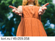 A young woman is standing in nature and is offering her hands to help. Стоковое фото, агентство Ingram Publishing / Фотобанк Лори